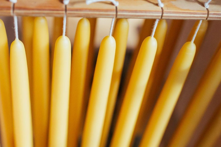 KI-generierte Beschreibung: Hauptinhalt des Bildes: Mehrere gelbe Kerzen in Reihen.