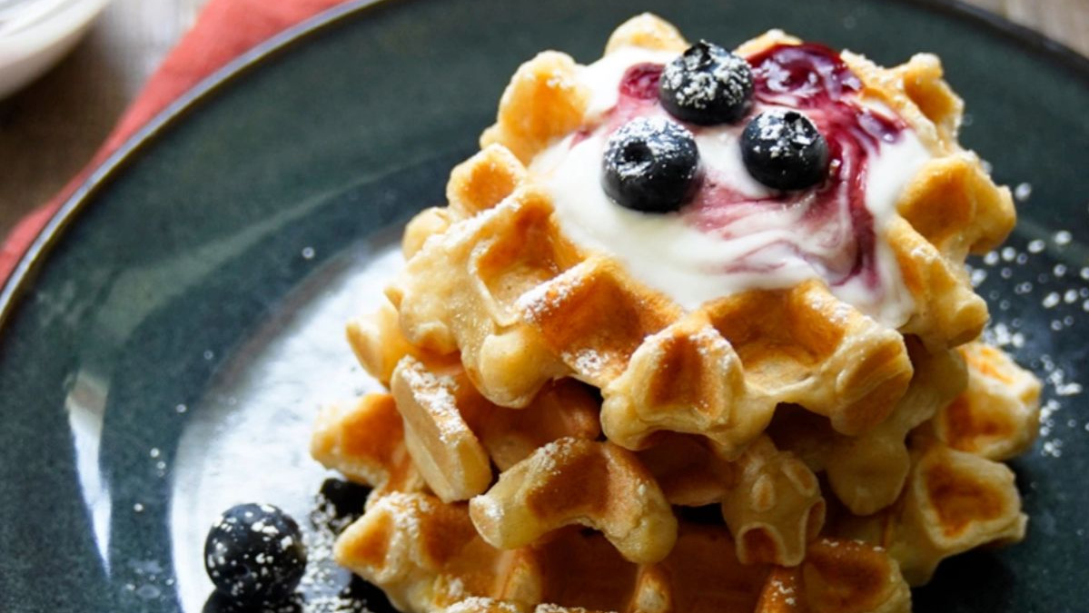 KI generiert: Das Bild zeigt eine Schüssel mit einem bunten Salat aus Rote-Bete-Scheiben, Karottenstreifen, Feldsalat, gehackten Nüssen und einem Klecks Sahne oder Joghurt in der Mitte. Der Salat liegt auf einem Holztisch.